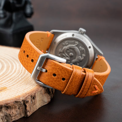 Side-stitched strap in brown vegetable-tanned leather with orange stitching